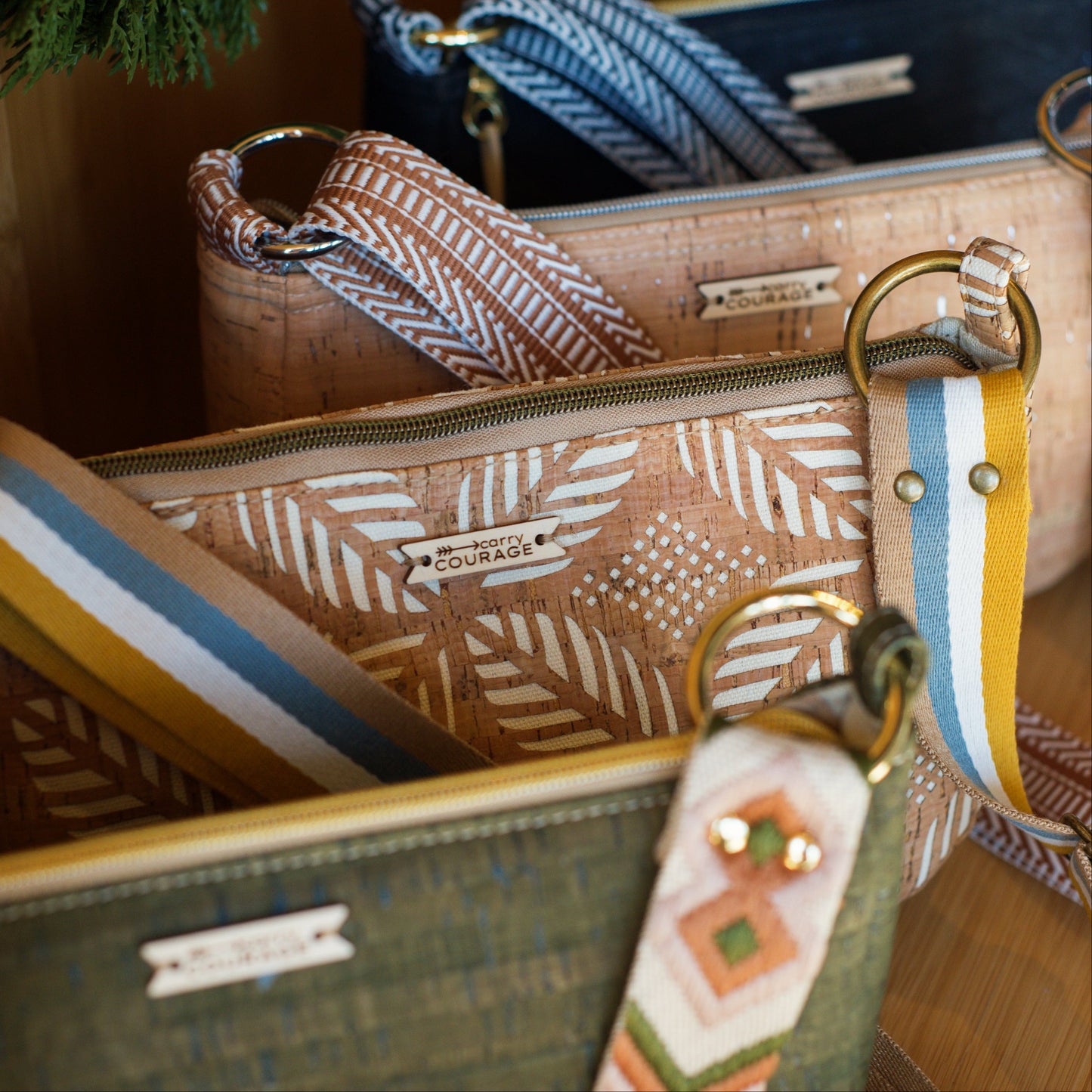 Close-up of a handbag with a strap featuring a decorative pattern, set against a wooden background.