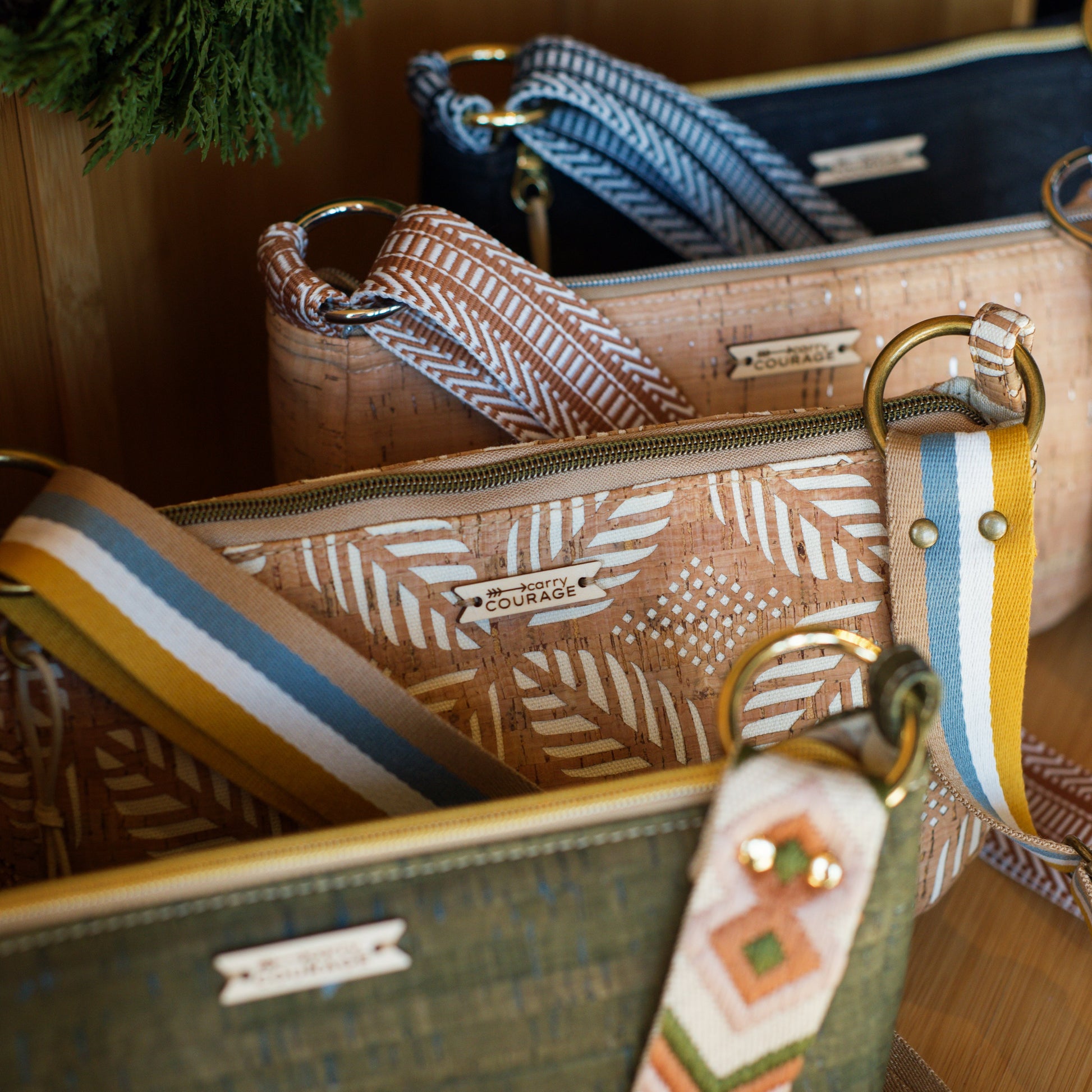 Close-up of a handbag with a strap featuring a decorative pattern, set against a wooden background.